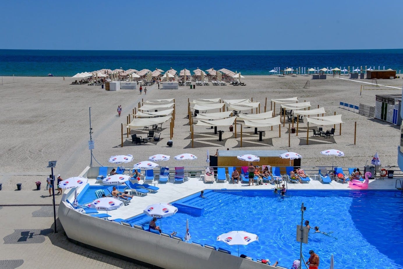 Piscină cu umbrele lângă plaja din Mamaia, cu marea în fundal