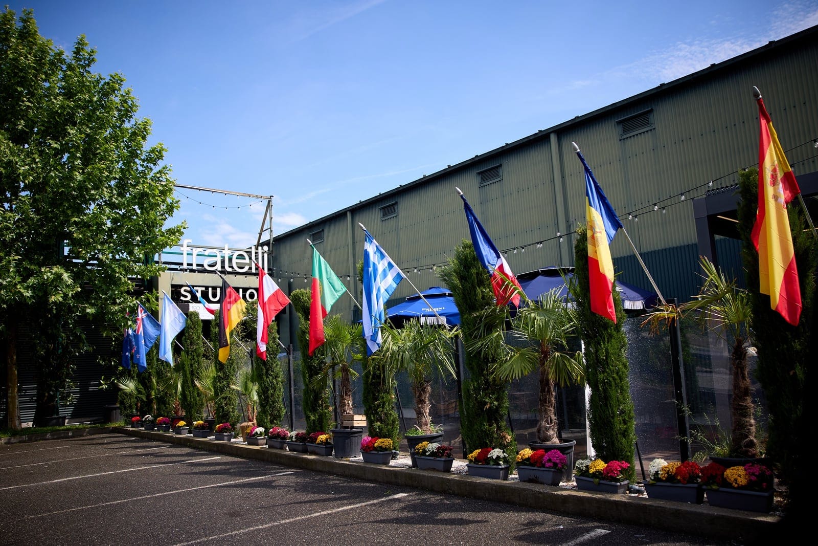 Intrarea în Fratelli Studios, decorată cu steaguri ale mai multor țări, palmieri și flori