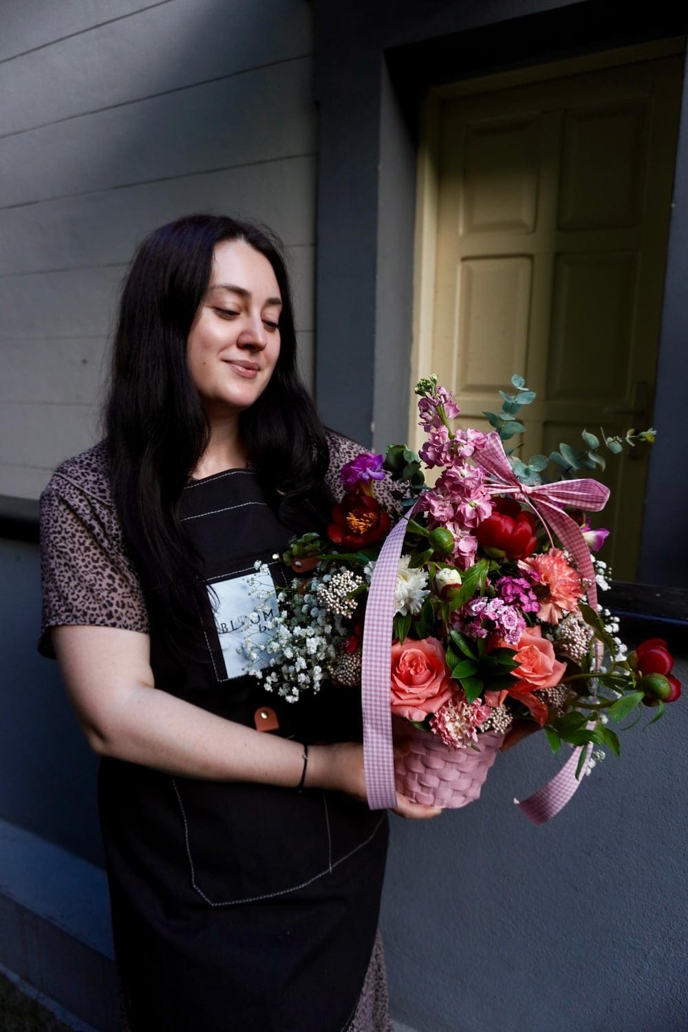 Florist cu șorț negru care ține un buchet mare de flori roz și albe