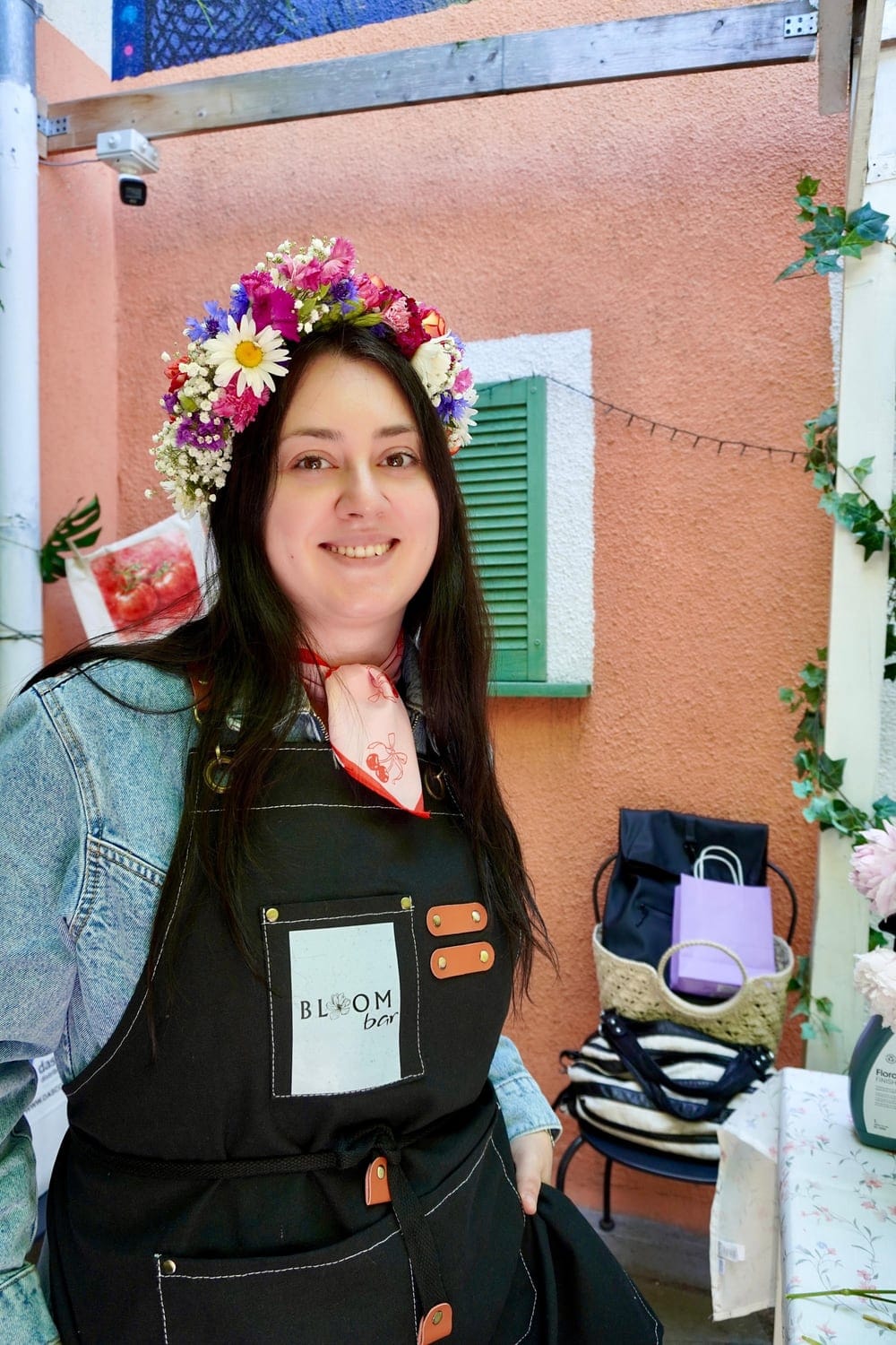 Femeie zâmbitoare cu o coroniță de flori și șorț negru