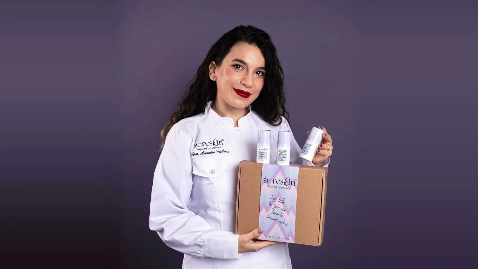 Alexandra Pașitoniu, cofondatoarea Sereskin, în halat alb, cu o cutie și trei produse ale brandului