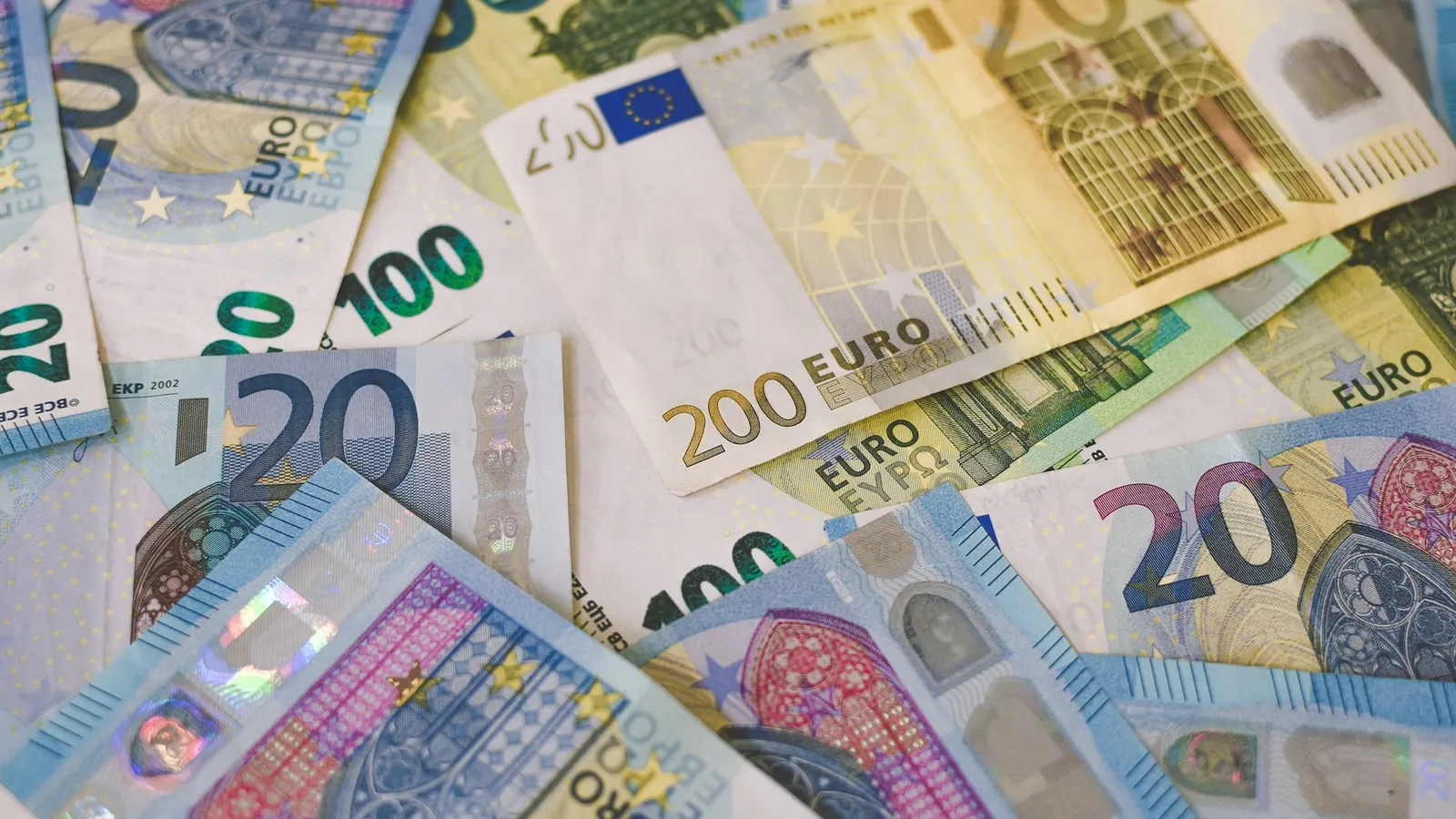 Bancnote euro de 20, 100 și 200 de euro, împrăștiate pe o masă