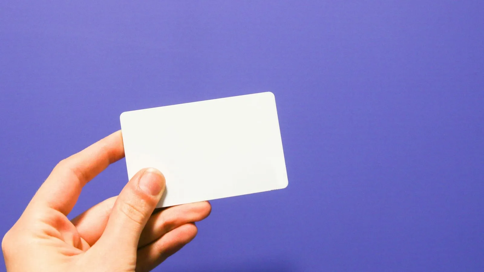 Mână care ține un card alb pe un fundal mov