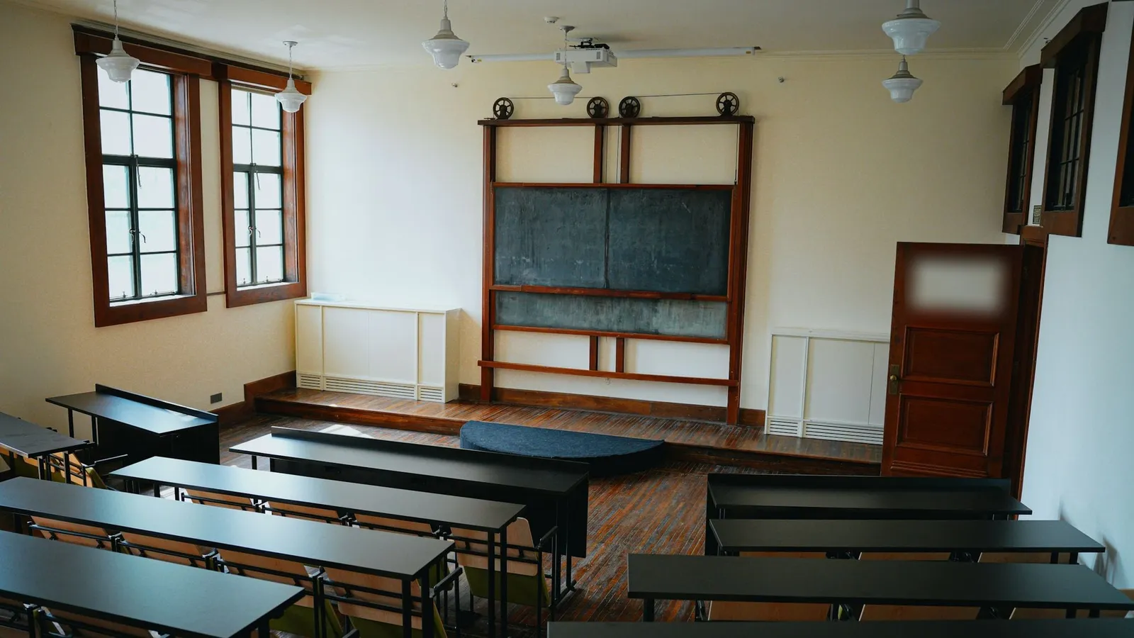 O sală de clasă goală, cu bănci și table de scris curate