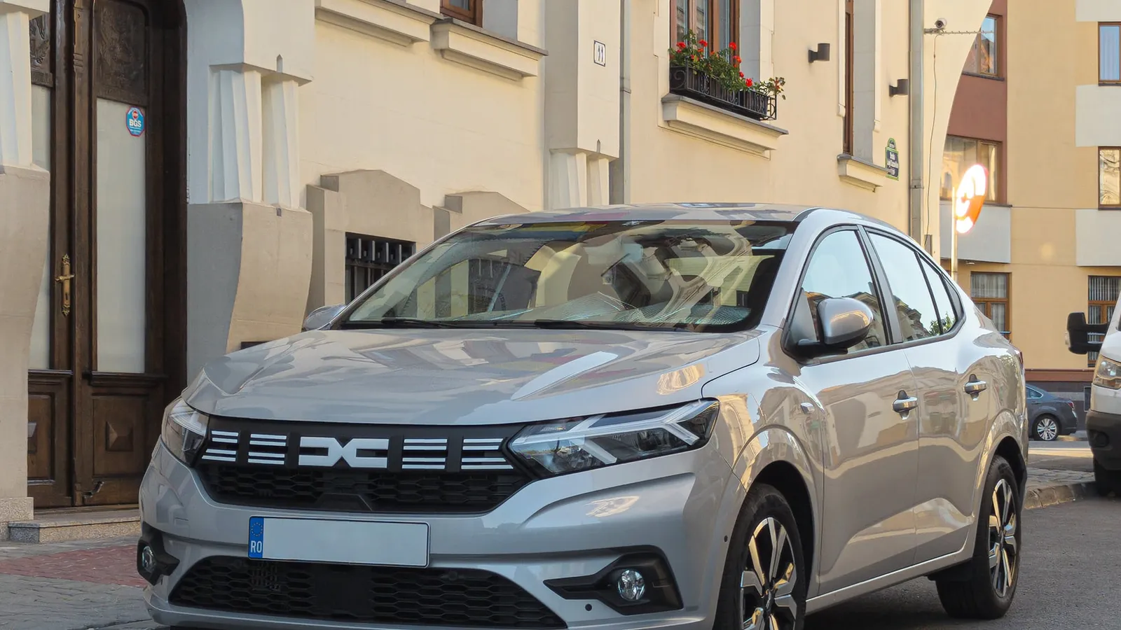 O Dacia Logan argintie, parcată pe o stradă