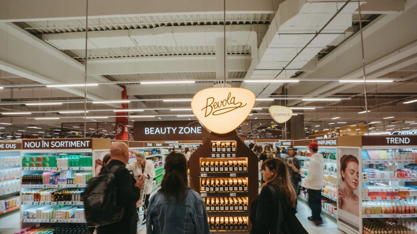 Clienți în noua zonă de cosmetice Beauty Zone dintr-un magazin Kaufland, cu standul Bevola în centru