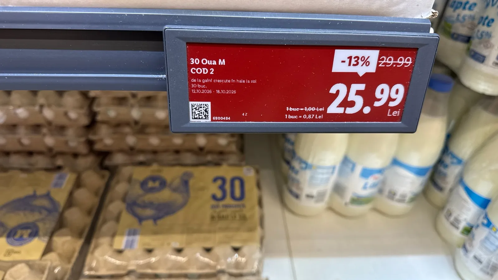 Eticheta de preț pentru 30 de ouă M de la găini crescute la sol, 25,99 lei redus de la 29,99 lei, deasupra cutiilor de ouă