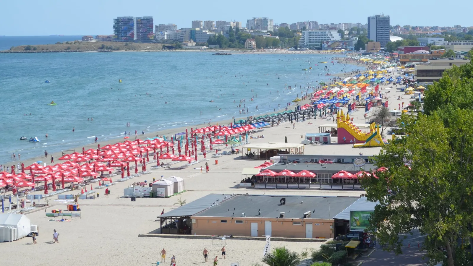 Plaja din Mamaia plină de turiști, cu umbrele colorate și hoteluri în fundal